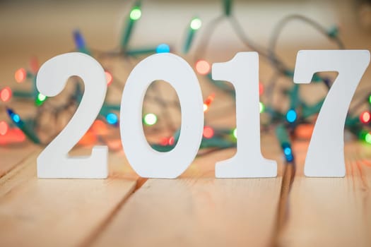 Numbers made of wood 2017 in front of colorful string of lights,selective focus