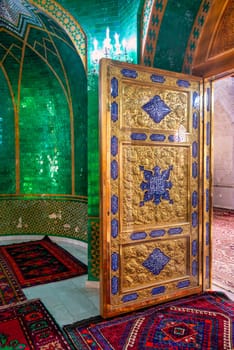 The interior of Bibi-Heybat Mosque in Baku, Azerbaijan features stunning green tiles, ornate details, and a beautifully crafted golden door of Ukeyma Khanum tomb