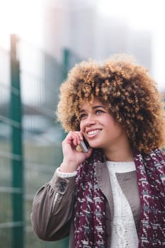 Woman talking on the phone outdoors. It is foggy and she is wearing warm clothing.