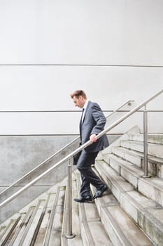 Businessman on his way to work. He is dressed in a formal suit and is walking down some steps.