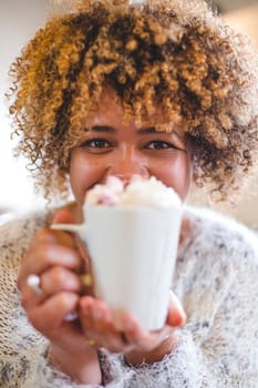 Woman posing for the camera with her hot chocolate held to her face.