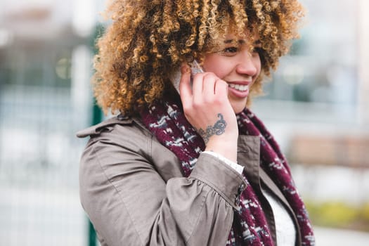 Woman talking on the phone outdoors. It is foggy and she is wearing warm clothing.