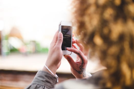 Over the shoulder shot of a woman using a smart phone to take a photo at a train station.