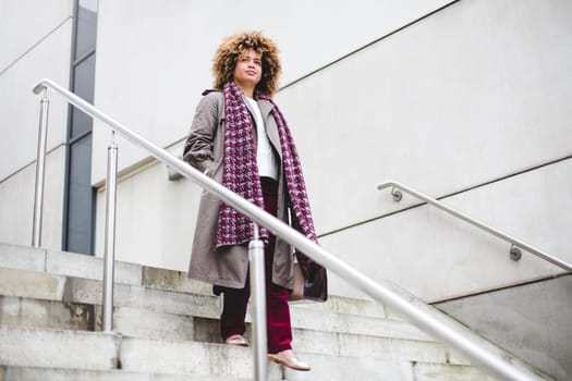 Businesswoman commuting to work in the city. She is walking down some stairs.