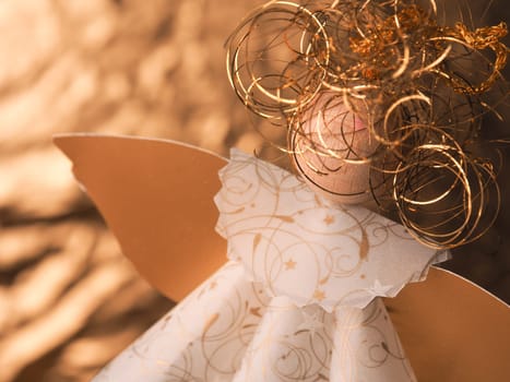 Golden homemade angel using as Christmas background, selective focus on the golden hair
