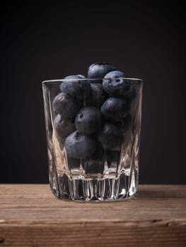 Blueberries in a glass on a wooden table, super food concept image