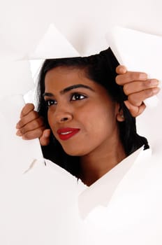 A pretty Indian woman with black hair looking trough a hole is a paper.with red lips, isolated for white background..