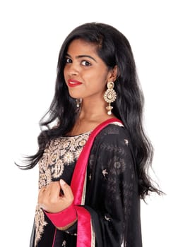 A gorgeous young Indian woman in a original Indian dress and long black.hair standing in profile isolated for white background..