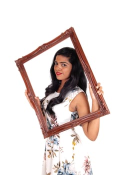 A beautiful Indian woman with long black hair holding up a picture frame.and looking trough, isolated for white background..