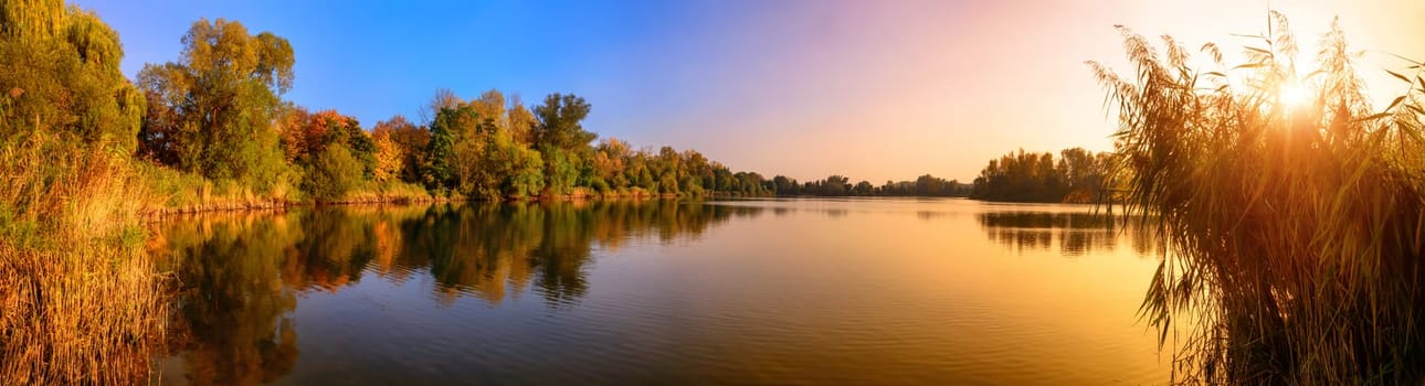 Panorama of a gorgeous sunset at a lake,with gold and blue color and trees reflected in the water
