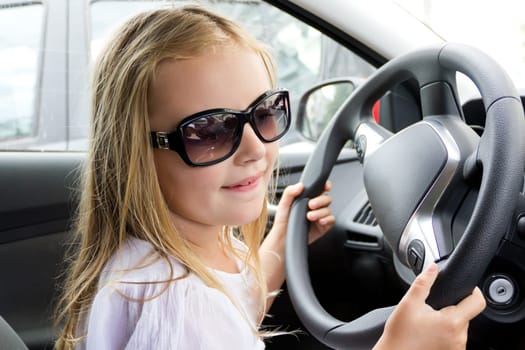 Cute girl driving car in sun glasses
