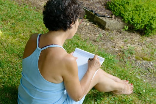 beautiful mature woman writes a letter in the garden