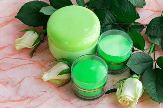 Set of three green cosmetic cream bottles with white roses