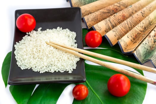 Oriental composition of rice, tomatoes, chopsticks, green leaf and transp isolated on white background