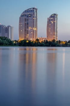Night city buildings reflected in river water. HDR