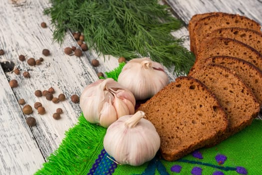 Still life on wooden background: black bread, garlic, fennel, bayberry pepper