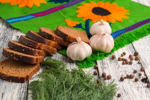 Still life on wooden background: black bread, garlic, fennel, bayberry pepper