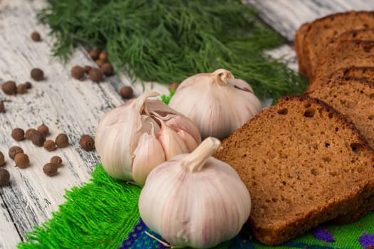Still life on wooden background: black bread, garlic, fennel, bayberry pepper