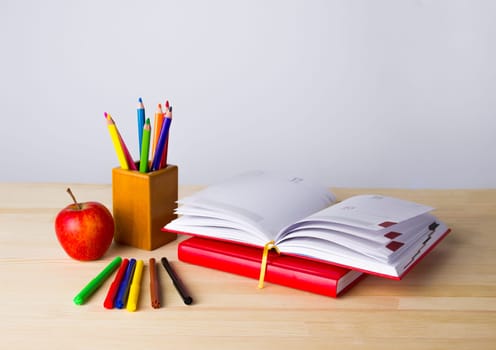 Back to school background with books, pencils and red apple over wooden table