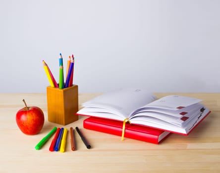 Back to school background with books, pencils and red apple over wooden table
