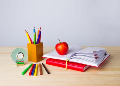 Back to school background with books, pencils and red apple over wooden table