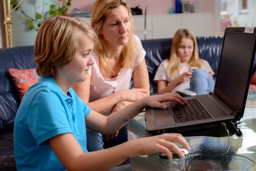 blond mother and her children using computer together