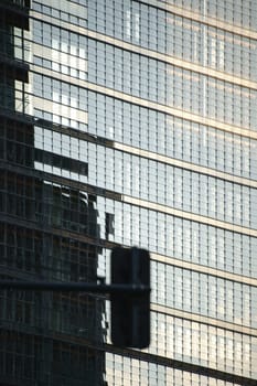 The modern façade of a high-rise building with mirrored windows and glass.