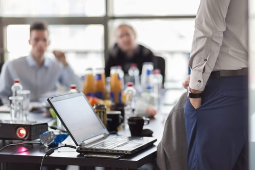 Business man making a presentation at office. Business executive delivering a presentation to his colleagues during meeting or in-house business training. Rear view. Business and entrepreneurship.