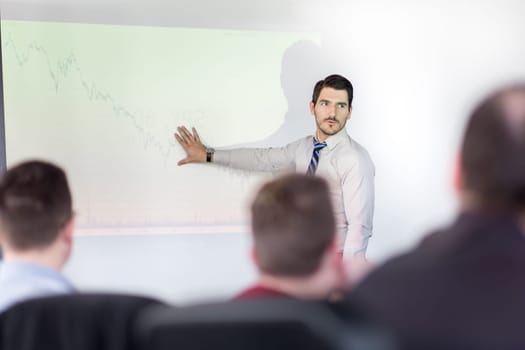Business man making a presentation at office. Business executive delivering a presentation to his colleagues during meeting or in-house business training, explaining business plans to his employees.