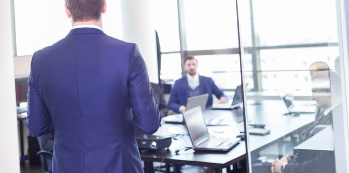 Business man making a presentation at office. Business executive delivering a presentation to his colleagues during meeting or in-house business training, explaining business plans to his employees.