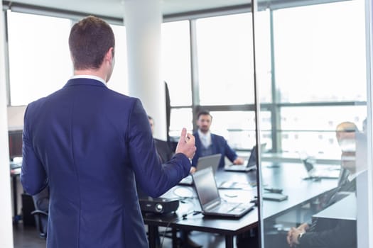 Business man making a presentation at office. Business executive delivering a presentation to his colleagues during meeting or in-house business training, explaining business plans to his employees.