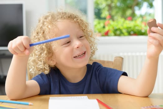 a little blond boy drawing in his home