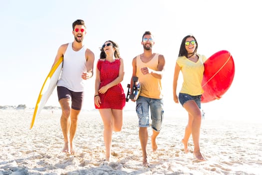 Group of friends walking together at the beach and holding surfboards