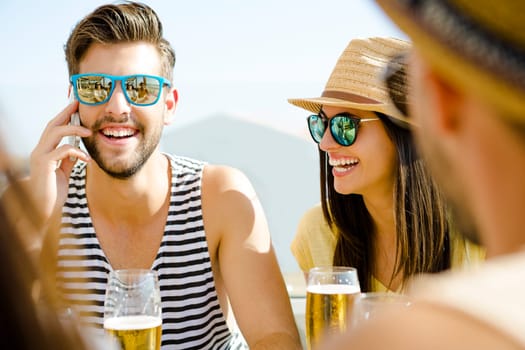 Friends having fun and drinking a cold beer at the beach bar