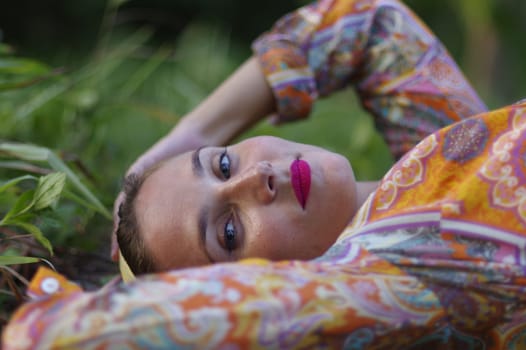 potrait of a young woman laying on grass, close up