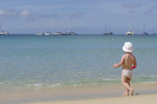 little girl standing with her back on the beach