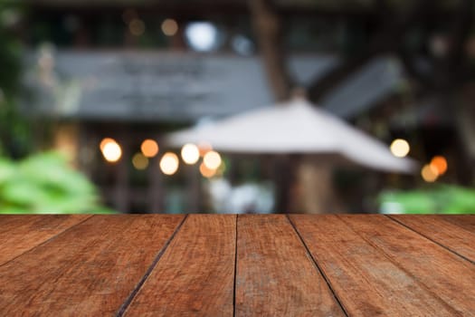 Wooden table top with cafe blurred abstract background