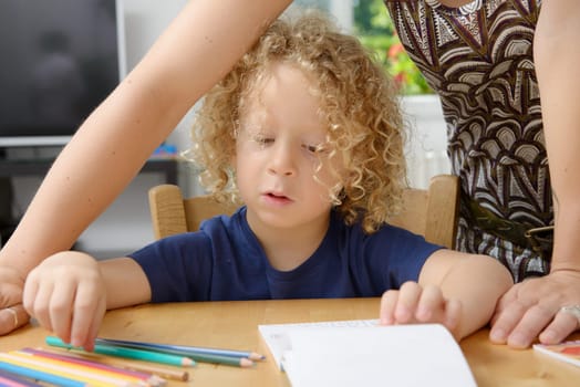a blond boy draws with his mom