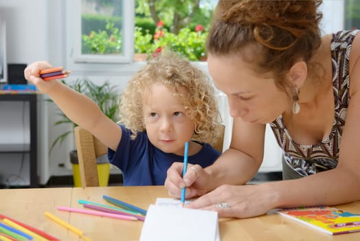 a blond boy draws with his mom