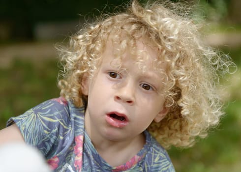 boy with curly blond hair, to the outside