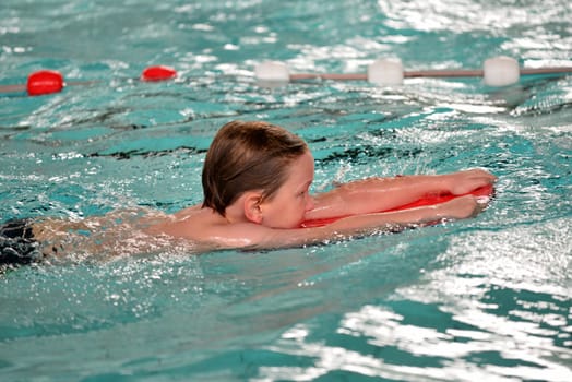 boy swimming with swimming board