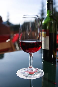 Local wine. Glass of red wine and the bottle at background. In the mountain chateau.