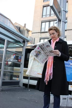 Zurich, Switzerland - November 28, 2011. Woman in pink scarf carefully studying newspaper