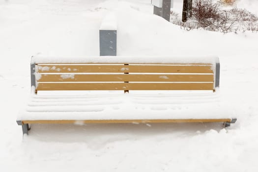 A wooden bench with a lair of snow on top of it