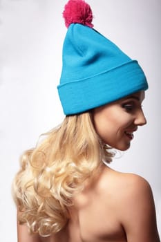 A woman in a knitted hat, stands back and looks down.