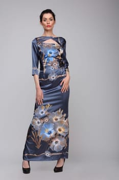Beautiful woman in full length posing in a long blue dress with flowers, isolated.