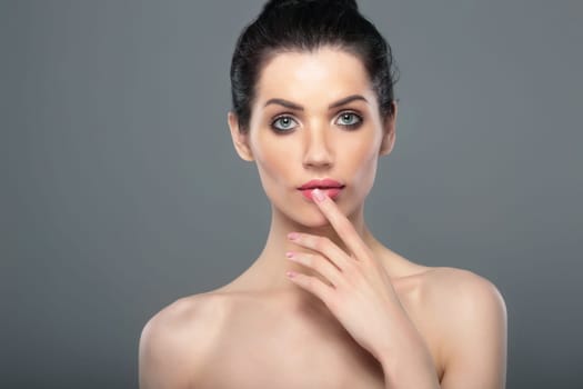 Perfect skin. Beautiful woman's face. Shoulders. Finger near lips.