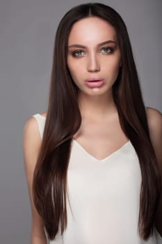 Beautiful young woman with clean skin, beautiful straight shiny hair, fashion makeup. Full lips.