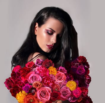 Fashion Beauty Model Girl with Flowers. Bouquet of Beautiful Flowers. The dress of flowers. Bright color. Professional makeup.