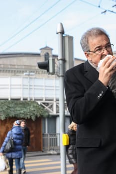 Zurich, Switzerland - November 29 2011. Ederly man eating a hamburger on the go.